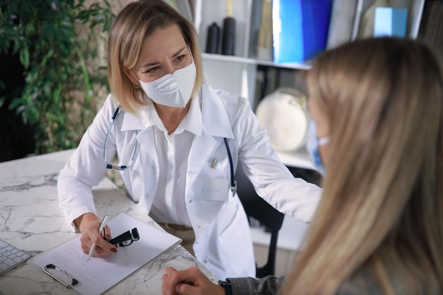 Friendly middle aged female doctor encouraging supporting patient after medical examination