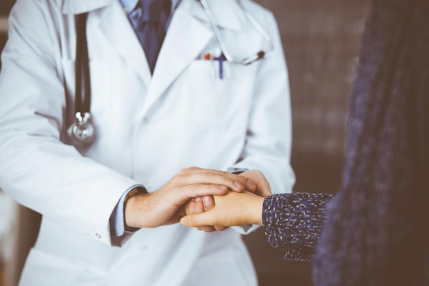 Friendly red-beard doctor reassuring his female patient, close-up. Medical ethics and trust concept, medicine theme.