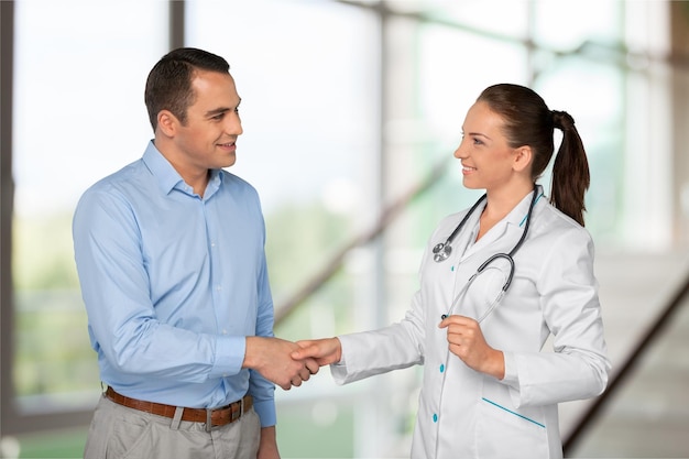 Friendly Senior doctor handshaking with young patient In white Office