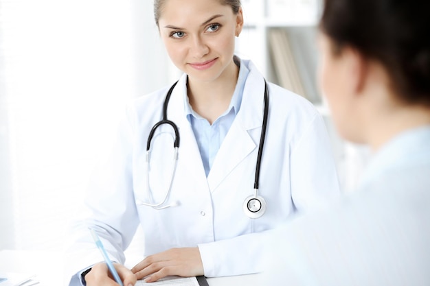 Friendly smiling doctor and patient sitting at the table. Very good news and high level medical service concept.