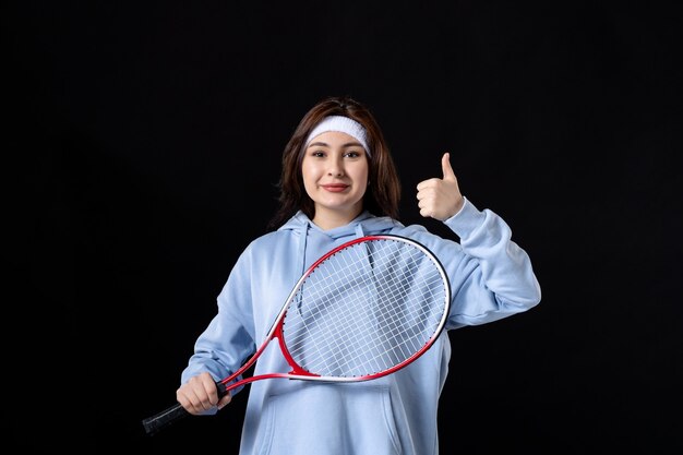 Friendly young female with racket on black