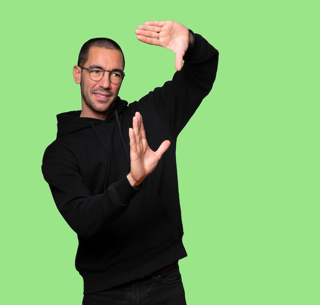 Friendly young man making a gesture of taking a photo with the hands