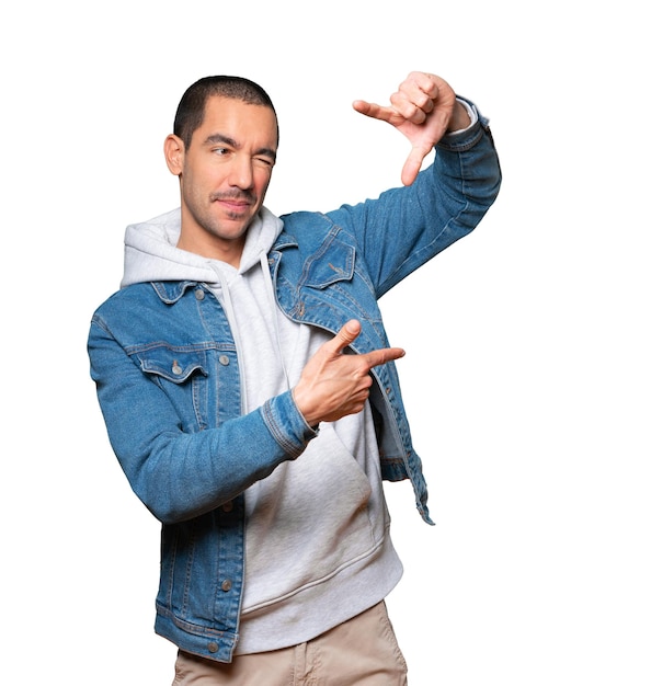 Friendly young man making a gesture of taking a photo with the hands