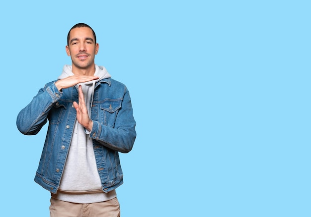 Friendly young man making a time out gesture with his hands