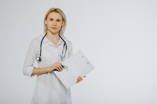 Friendly young nurse holding a clipboard medical record and a pen isolated over a white