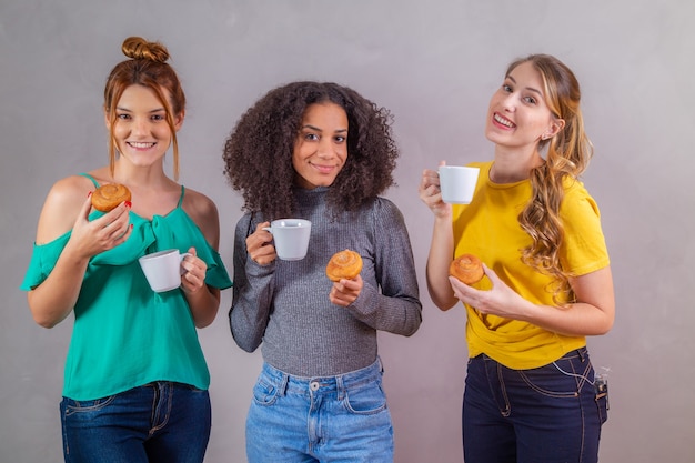 Friends at afternoon tea eating donuts and drinking coffee with milk