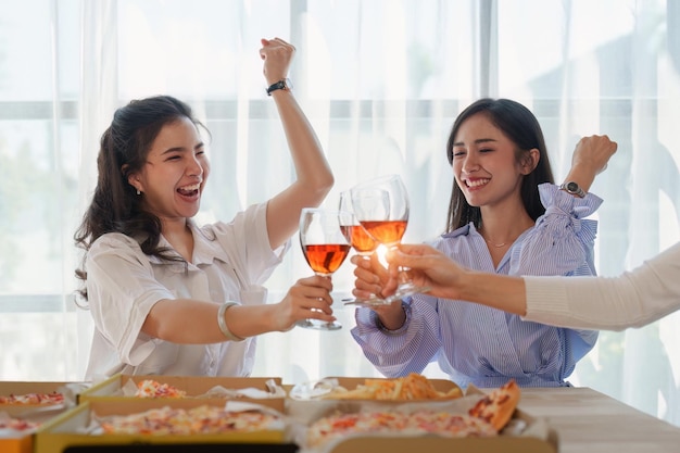 Friends at birthday party clinking glasses with champagne and pizza enjoying Christmas vacation pizza on the table Holiday Party event