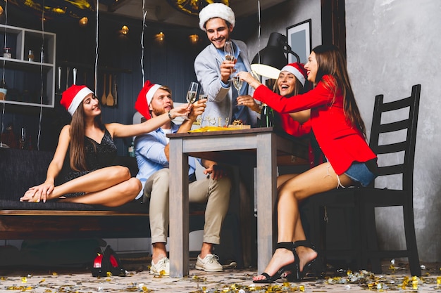 Friends celebrating Christmas or New Year eve. Party table with champagne