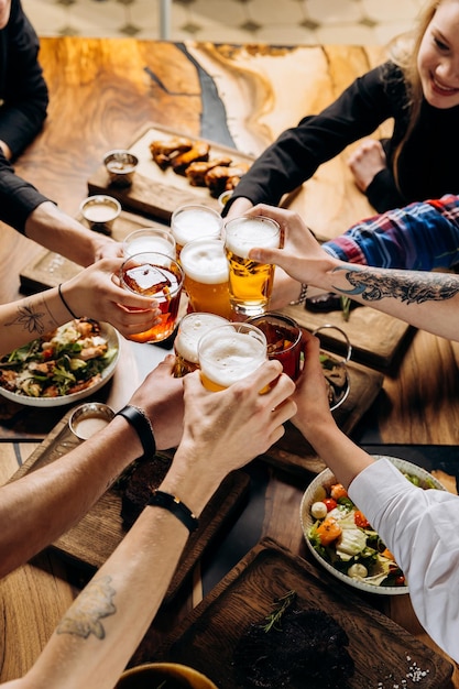 Friends cheering beer glasses on wooden table with food food and beverage lifestyle concept