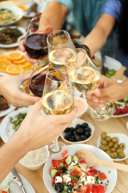 Friends cheering with glasses of wine on picnic