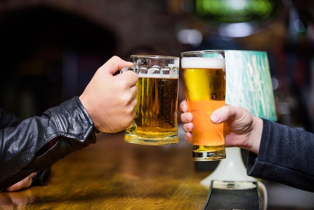 Friends cheers glasses Friday leisure tradition Beer pub concept Beer mug on bar counter defocused background Glass with fresh lager draft beer with foam Mug filled with cold tasty beer in bar