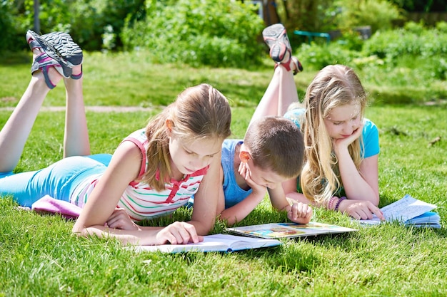 Friends children reading books outdoori on grass