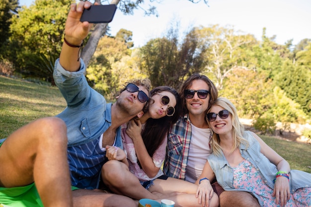 Friends clicking selfie while having picnic