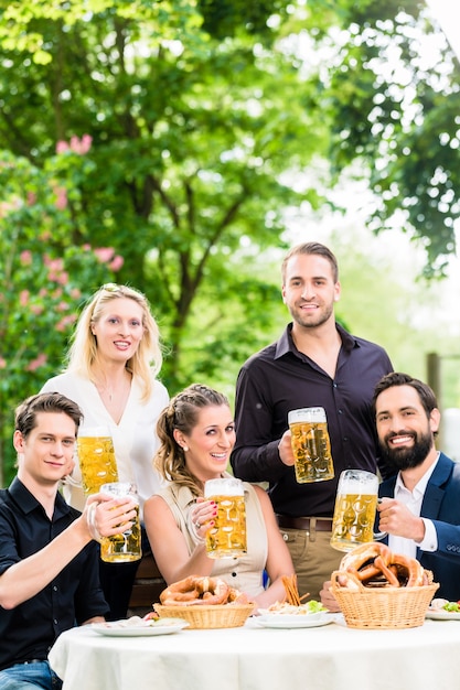 Friends or colleagues on beer garden after work toasting with drinks