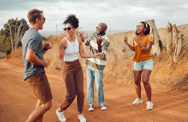 Friends dance and nature with a man and woman group having fun outdoor during travel or adventure together Summer vacation and freedom with young people dancing on a sand road in the desert