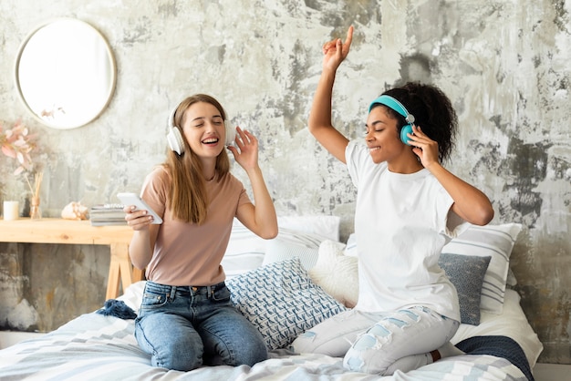 Friends dancing on bed at home