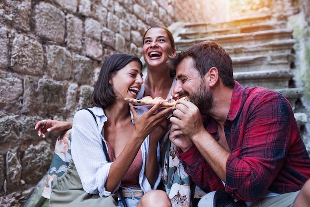 Friends eating delicious pizza at street