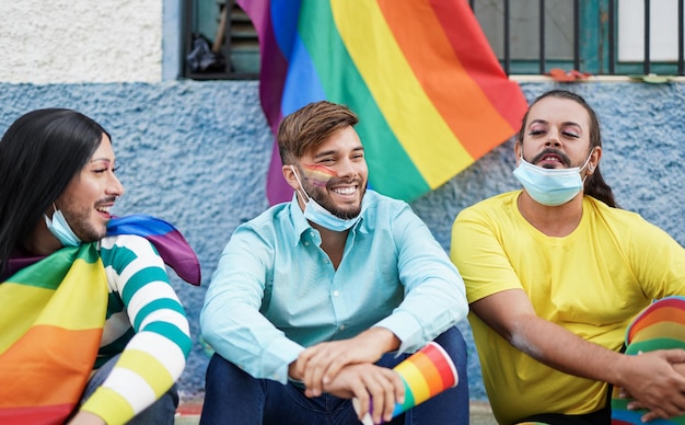 Friends enjoying the lgbt parade - Gay men and transgender wearing surgical face mask under chin for coronavirus outbreak