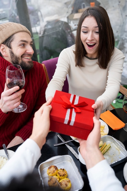 Friends exchanging gift during a reunion while having lunch