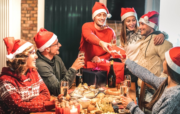 Friends group wearing santa hat giving each other Christmas presents