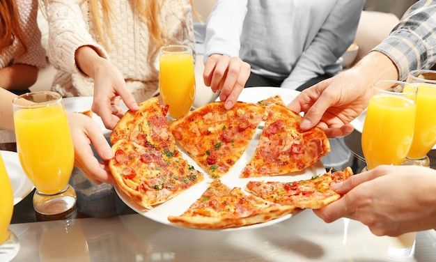 Friends hands holding hot pizza close up