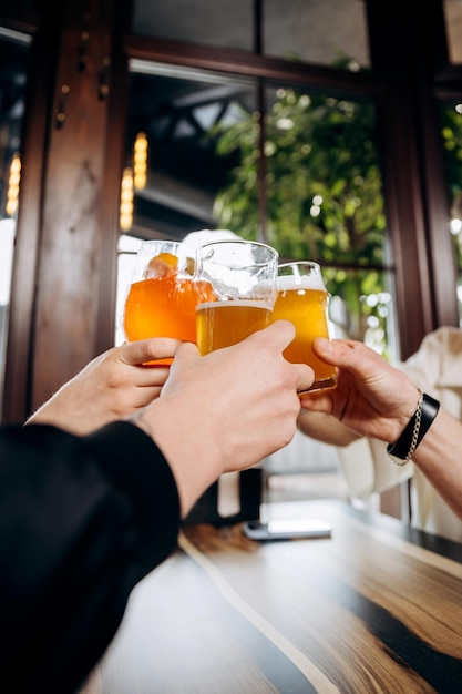 Friends hands toasting and having fun together drinking beer and cocktails at happy hour in pub restaurant Social life style party time concept