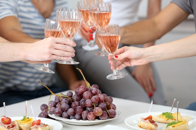 Friends hands with glasses of wine and snacks, close up