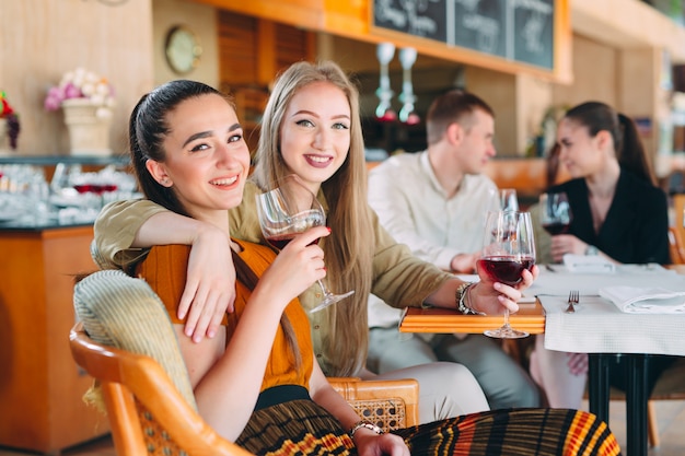 Friends have fun drinking wine, talking and smiling in the restaurant.