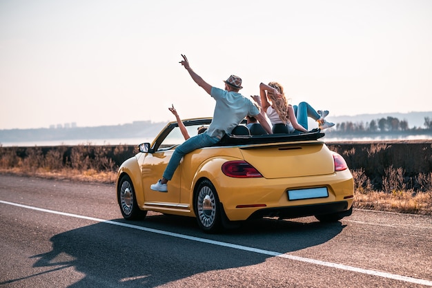 The friends have fun traveling by a cabriolet