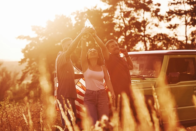 Photo friends have nice weekend outdoors near theirs green car with usa flag