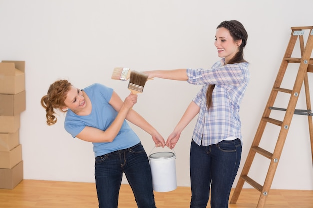 Friends holding paint brushes and can in a new house