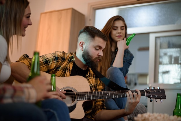 Friends on a house party playing guitar and having fun