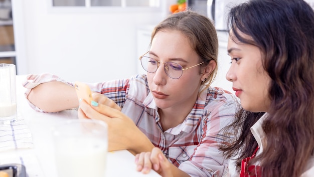 friends in kitchen Woman at breakfast table Looking at Partner Messaging On Social Media