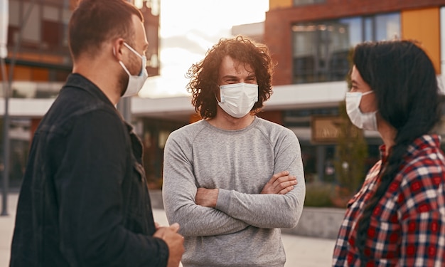 Friends in masks meeting on city street