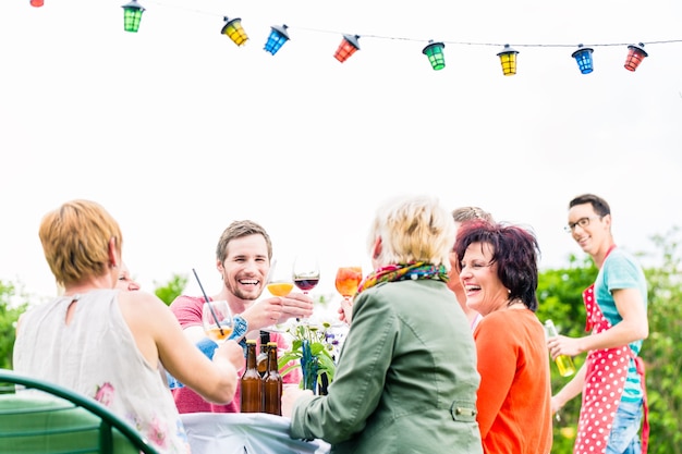 Friends and neighbors on long table celebrating party toasting with drinks