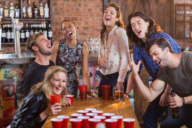 Friends playing beer pong on table