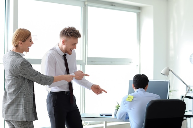 Friends playing a prank on their colleague in office. April Fools' Day prank