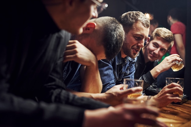 Friends resting in the pub with alcohol in hands