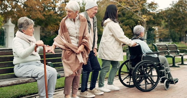 Friends retirement and senior people in park for bonding conversation and quality time together outdoors Friendship happy and elderly man and women with caregiver on bench for relaxing in nature