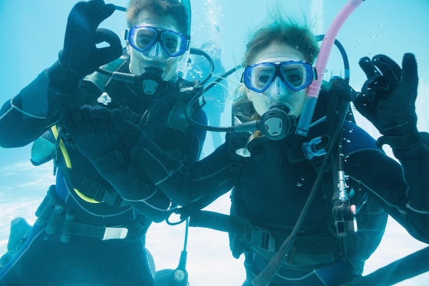 Photo friends on scuba training submerged in swimming pool looking to camera