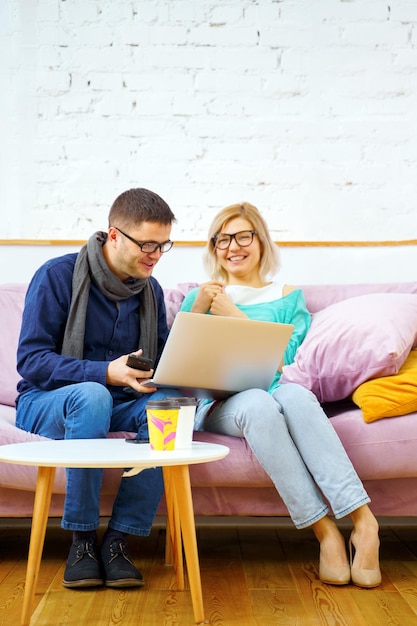 Friends sit on the couch chatting and using a desktop computer