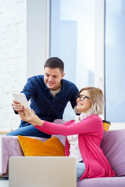 Friends sit on the couch chatting and using a tablet computer