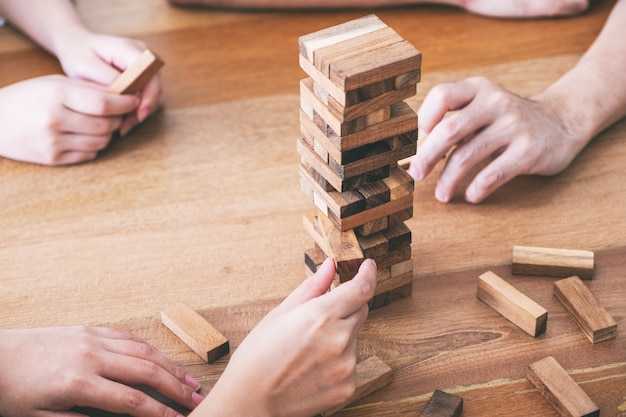 Friends sitting and playing Tumble tower wooden block game together