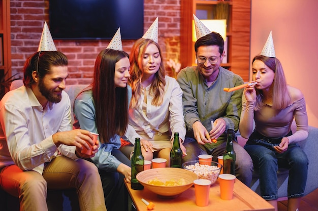 Friends sitting on a sofa in a cozy room and celebrating birthday