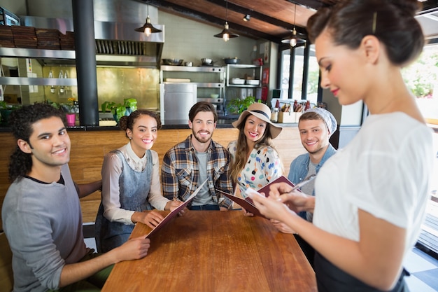 Friends sitting while waitress taking orders in restaurant