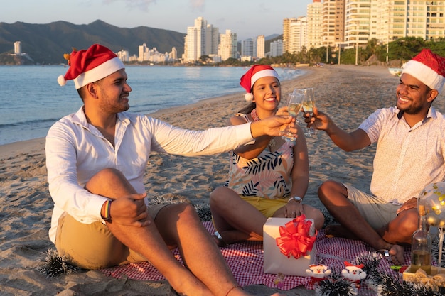 Friends smiling and proposing a toast as they sit celebrating the New Year on the beach.