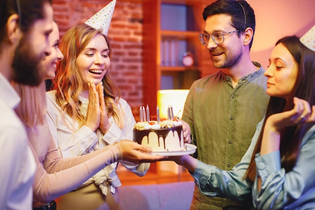 Friends standing together holding a plate with a cake and celebrating birthday