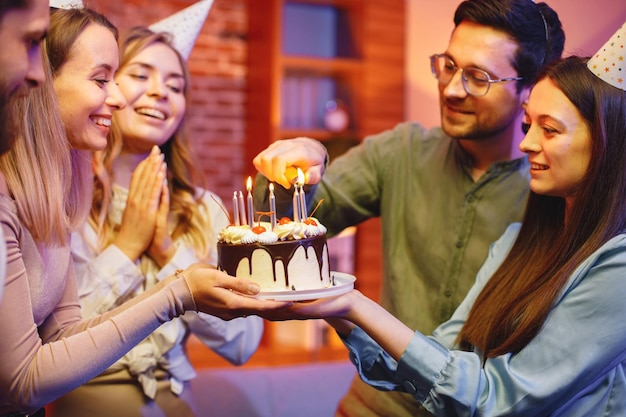 Friends standing together holding a plate with a cake and celebrating birthday