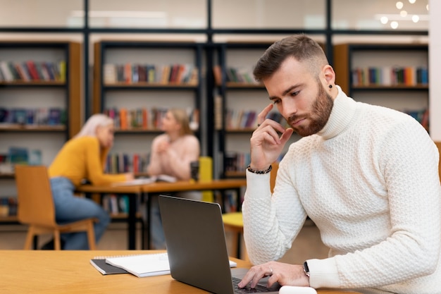 Friends studying using a laptop and books in a library