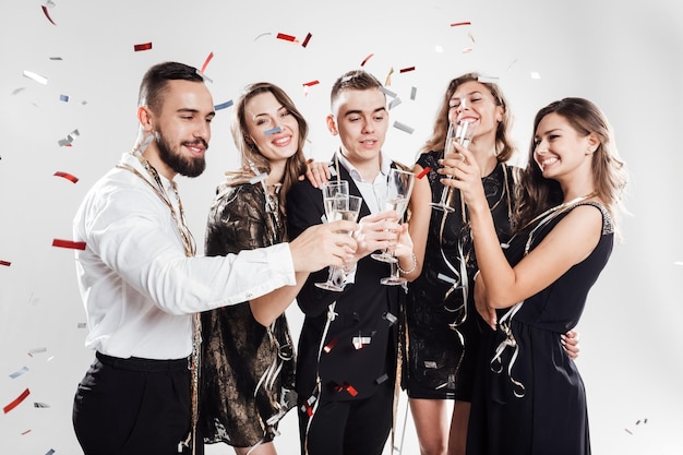 Friends in stylish elegant clothes smile together holding glasses of champagne in hands